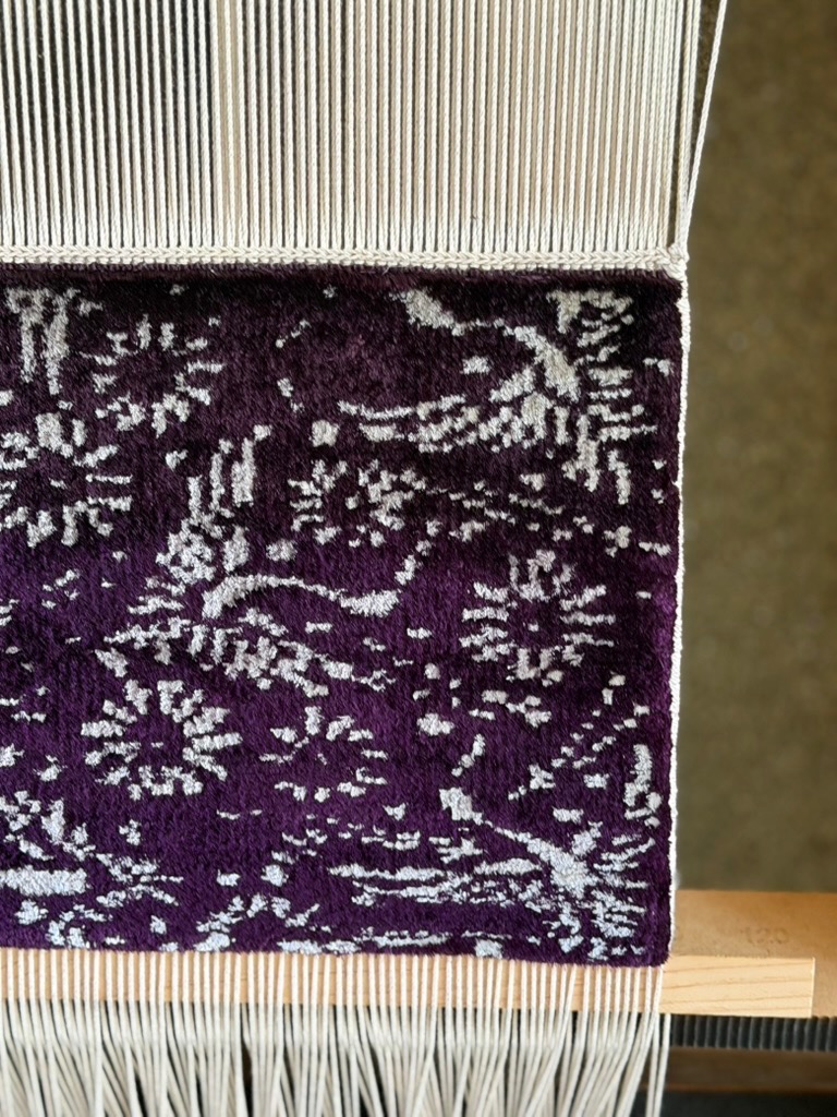 緞通の文様の全体。紫地に白い花と唐草。